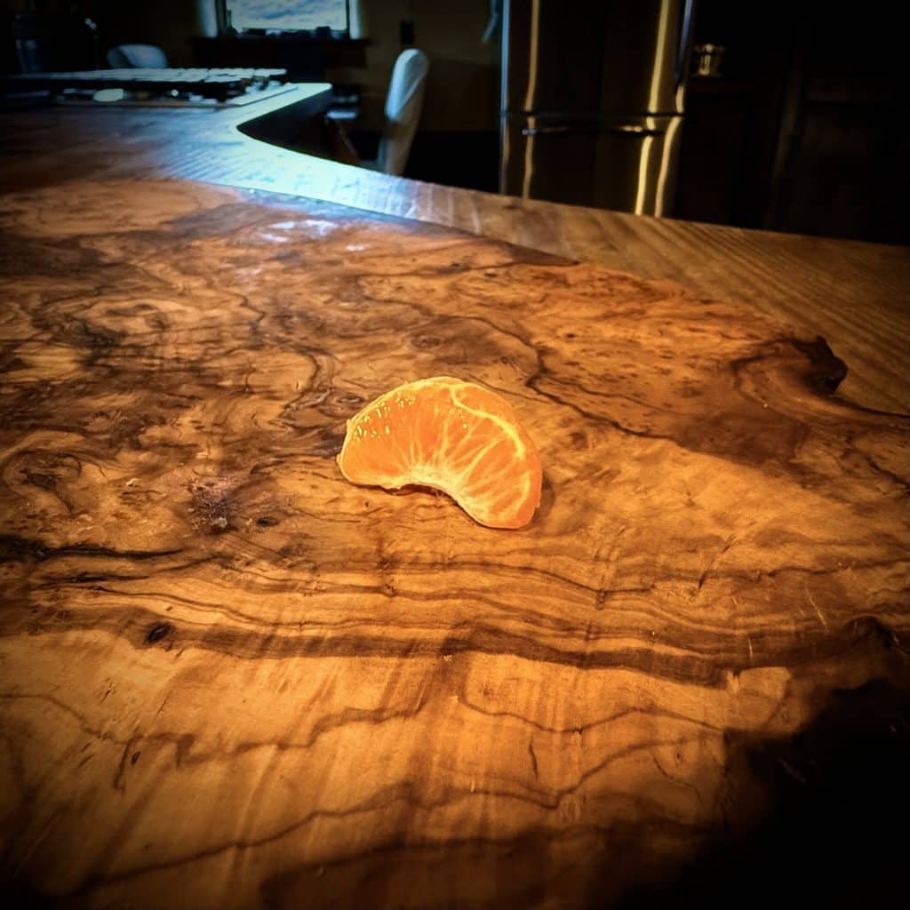 One little lonely orange on a burly cutting board.